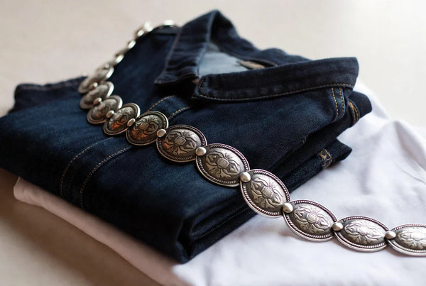 Concho belt styled with denim and a crisp shirt in a refined editorial flat lay