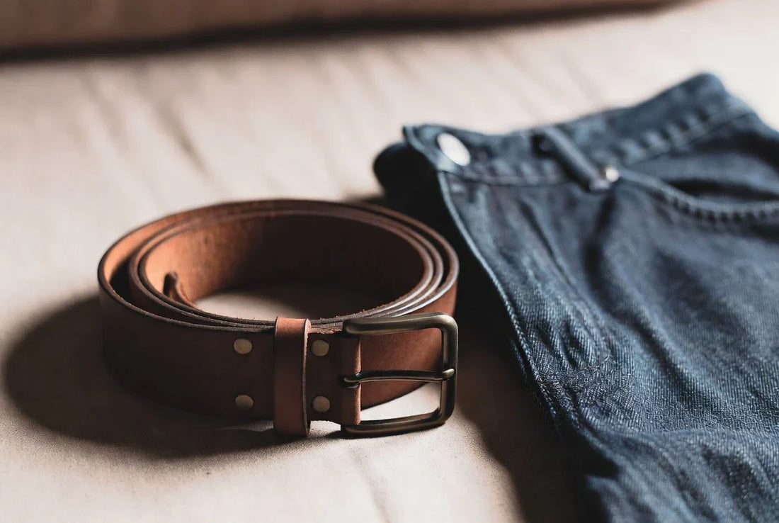 Editorial workwear scene with a casual leather belt beside denim and cotton trousers