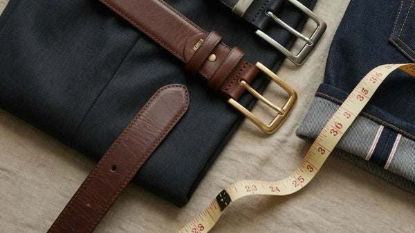 Leather belts styled with trousers, denim, and a measuring tape for a guide on how to size a belt