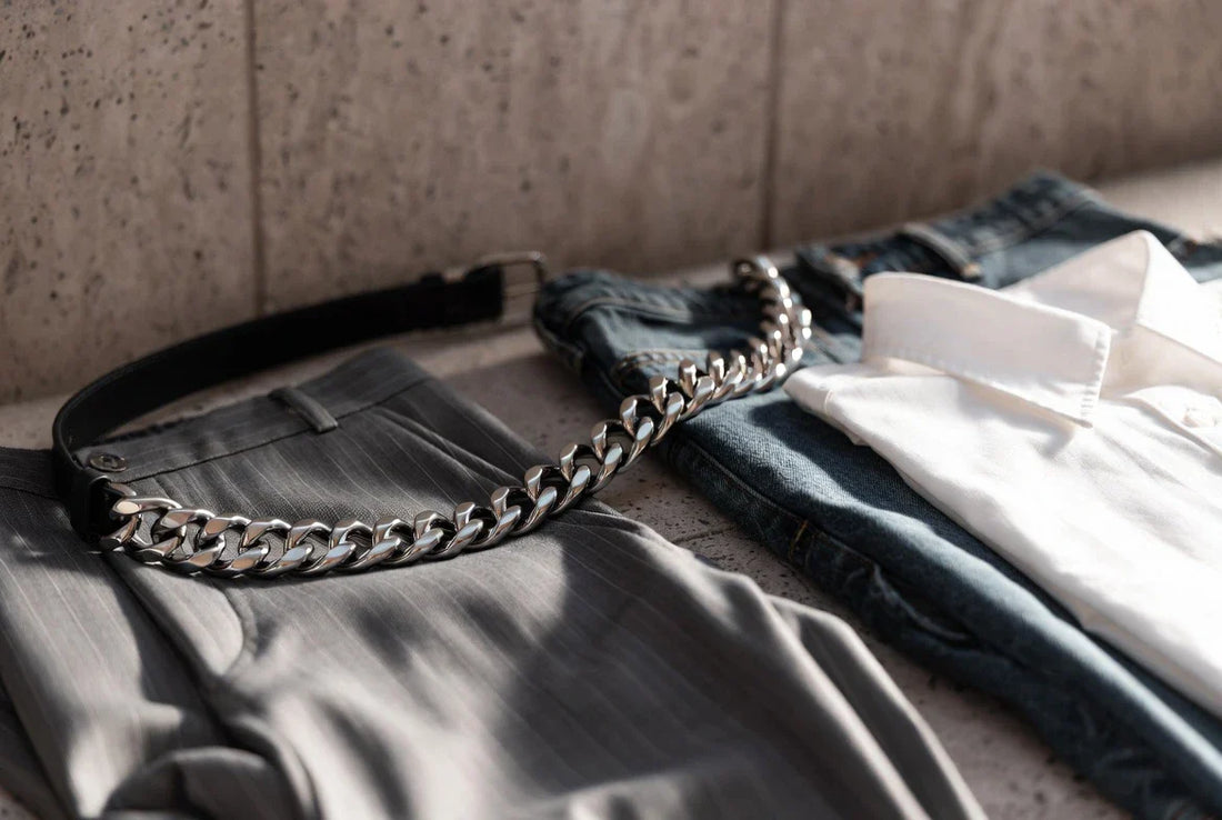 Editorial flat lay of a polished link belt with tailored trousers and denim for a fit and proportion guide