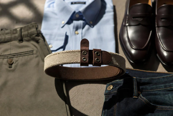 Needlepoint belt styled with chinos, denim, and classic wardrobe pieces in an editorial flat lay