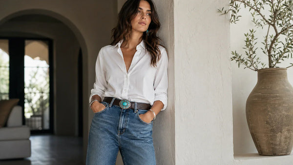 Woman styling a leather belt with a turquoise buckle with jeans and a simple shirt