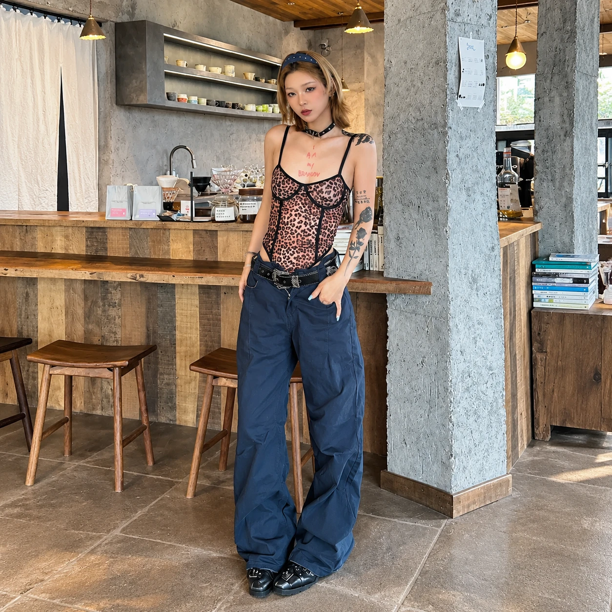Black belt for women styled with low-rise navy trousers and a leopard-print top for a vintage-inspired Y2K look