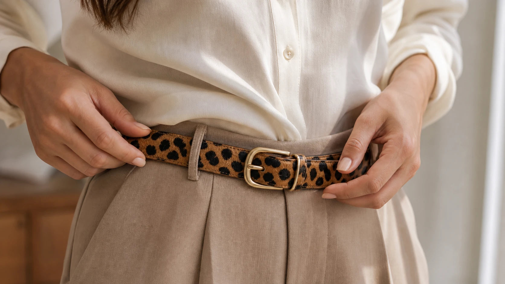 Woman adjusting a cheetah print belt to show proper fit and buckle placement
