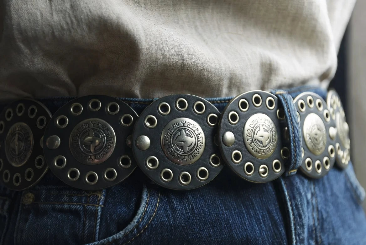 Close-up of a concho belt positioned evenly through denim loops with balanced spacing at the waist
