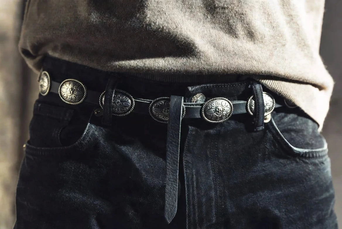 Concho belt worn with a tucked neutral knit and dark jeans showing neat tail length and balanced front placement